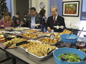 In this Dec. 15, 2017 photo, Tri Phan, right, begins the lunch line for his retirement party at Lutheran Social Services in Fargo, N.D. Phan, 66, spent nearly three decades working in the agency's refugee resettlement program, helping thousands of immigrants from dozens of countries become U.S. citizens. Phan, who was born in Saigon, is moving to California to be closer to his grown children.