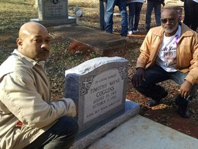 Ramon, left, and Tyrone Coggins, brothers of Timothy Wayne Coggins, pose beside the new headstone on Timothy Coggins' grave in Zebulon, Ga. Saturday, Dec. 30, 2017.  Timothy Wayne Coggins was killed in 1983. His slaying remained unsolved for decades. In October 2017, authorities charged two men with killing him. Prosecutors said the black victim was killed for socializing with a white female. The Coggins family dedicated the new headstone on Saturday.