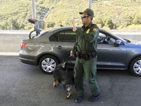 In this Thursday, Dec. 14, 2017 photo, a border patrol agent stops a vehicle at a checkpoint in Pine Valley, Calif. California legalizes marijuana for recreational use on Monday, Jan. 1, 2018, but that won't stop federal agents from seizing small amounts on busy freeways and backcountry highways. Marijuana possession will continue to be prohibited at eight Border Patrol checkpoints in California, a reminder that state and federal law collide when it comes to pot.
