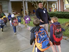 In this Nov. 6, 2017 photo, campus monitor Hector Garcia greets students as they got off the bus at the start of the school day at West Elementary School in New Canaan, Conn. Garcia and the district's other campus monitors -- all former police or corrections officers -- were among a wave of security officers hired in the aftermath of the deadly school shooting in nearby Newtown on Dec. 14, 2012.