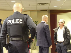 St. Catharines Standard reporter Bill Sawchuk, right, is addressed by Niagara Region senior staffer Chris Carter while being ejected from regional council chambers and removed from the property under police escort.