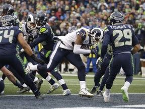 Los Angeles Rams running back Todd Gurley, second from right, rushes for a touchdown as Seattle Seahawks' Bobby Wagner (54) and Earl Thomas (29) look on in the first half of an NFL football game, Sunday, Dec. 17, 2017, in Seattle.