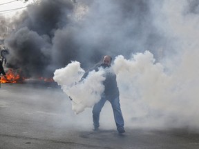 A Palestinian protester tries to throw a gas canister shot by Israeli soldiers during a demonstration in the West Bank city of Bethlehem, Friday, Dec. 22, 2017. Palestinians have been clashing with Israeli troops across the West Bank and along the Gaza border since Trump's announcement.