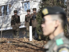 FILE - In this Nov. 27, 2017, file photo, North Korean soldiers look at the South side as a South Korean stands guard near the spot where a North Korean soldier crossed the border on Nov. 13 at the Panmunjom, in the Demilitarized Zone, South Korea. South Korea says on Thursday, Dec. 21, 2017, it has fired 20 rounds of warning shots as North Korean soldiers approached a military demarcation line at the border after their comrade defected to South Korea.