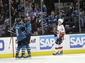 San Jose Sharks' Joe Pavelski, left, celebrates his goal with teammate Joe Thornton, center, while Calgary Flames' Mikael Backlund (11) skates past during the first period of an NHL hockey game Thursday, Dec. 28, 2017, in San Jose, Calif.