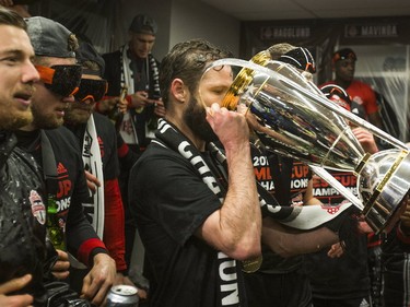 Toronto FC players drink from the MLS Cup in their dressing room.