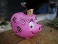 A piggy bank for tips, filled with five Bolivar bills, sits on the table of a vegetable vendor at a market in Caracas, Venezuela.