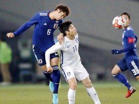 Japan's Genta Miura, left, and South Korea's Lee Keunho vie for the ball at the East Asian Championship in Tokyo, Saturday, Dec. 16, 2017.