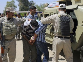 FILE - In this April 5, 2015, file photo, blindfolded and handcuffed men are lead to custody after being arrested in Hillah, about 60 miles (95 kilometers) south of Baghdad, Iraq. The Iraqi security forces arrested three men during a recent security operation in the city who they suspected of members of the Islamic State group. Human Rights Watch said in a report released on Tuesday, Dec. 5, 2017, that thousands of people suspected of having ties to the Islamic State group face widespread rights violations in Iraqi custody. (AP Photo, File)