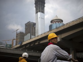 FILE - In this Aug. 16, 2017, file photo, a construction worker waits to cross an intersection near buildings under construction in the central business district of Beijing. The World Inequality Report 2018 released Friday, Dec. 15, 2017, is based on a massive collection of data compiled by an international team of researchers. It shows inequality has soared since 1980 although the global top "1 percent" saw their share of global income shrink slightly after the global financial crisis. The share of global income going to the bottom 50 percent rose slightly, to just under 10 percent, thanks to gains in populous, fast-growing China and India.