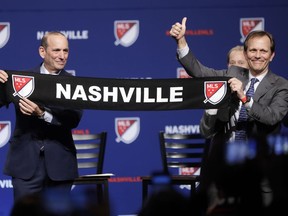 Major League Soccer commissioner Don Garber, left, presents a scarf to John Ingram, chairman of Ingram Industries Inc., as Garber announces that Nashville, Tenn. has been awarded a Major League Soccer franchise Wednesday, Dec. 20, 2017, in Nashville, Tenn. Ingram is the head of the group seeking to bring the team to Nashville.