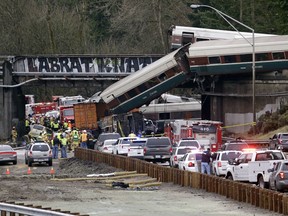 Cars from an Amtrak train lay spilled onto Interstate 5 below as some remain on the tracks above Monday, Dec. 18, 2017, in DuPont, Wash. The Amtrak train making the first-ever run along a faster new route hurtled off the overpass Monday near Tacoma and spilled some of its cars onto the highway below, killing some people, authorities said. Seventy-eight passengers and five crew members were aboard when the train moving at more than 80 mph derailed about 40 miles south of Seattle before 8 a.m., Amtrak said. (AP Photo/Elaine Thompson)