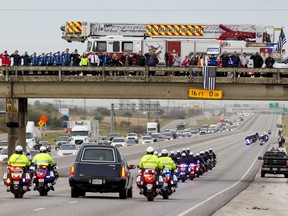 People salute as the funeral procession for San Marcos Police officer Kenneth Copeland passes on Interstate 35 in San Marcos, Texas, on Wednesday, Dec. 13, 2017. Copeland was fatally shot last week while trying to serve a warrant on a domestic violence suspect.