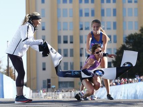 In this Sunday, Dec. 10, 2017, photo, Ariana Luterman, 17, back, helps Chandler Self, center, at the finish line during the BMW Dallas Marathon in Dallas, as Shalane Flanagan, four-time Olympian, left, watches.