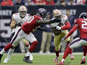 San Francisco 49ers running back Carlos Hyde (28) is grabbed by Houston Texans outside linebacker Jadeveon Clowney (90) during the first half of an NFL football game, Sunday, Dec. 10, 2017, in Houston.