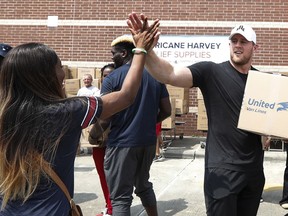 FILE - In this Sept. 3, 2017, file photo, Anna Ucheomumu, left, high-fives Houston Texans defensive end J.J. Watt after loading a car with relief supplies to people impacted by Hurricane Harvey in Houston. Watt's work in hurricane relief came in second on this year's list of Top 10 Communication Moments, as compiled by Decker Communications.