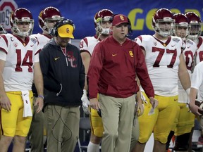 Southern California coach Clay Helton, center, stands on the sidelines with quarterback Sam Darnold (14), guard Chris Brown (77) and others during the first half of the Cotton Bowl NCAA college football game against Ohio State in Arlington, Texas, Friday, Dec. 29, 2017.