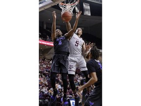 Texas A&M guard Savion Flagg (5) dunks as Buffalo guard CJ Massinburg (5) defends during the first half of an NCAA college basketball game Thursday, Dec. 21, 2017, in College Station, Texas.