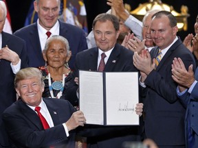 President Donald Trump holds up a signed proclamation to shrink the size of Bears Ears and Grand Staircase Escalante national monuments at the Utah State Capitol Monday, Dec. 4, 2017, in Salt Lake City. Trump traveled to Salt Lake City to announce plans to shrink two sprawling national monuments in Utah in a move that will delight the state's GOP politicians and many rural residents who see the lands as prime examples of federal overreach, but will enrage tribes and environmentalist groups who vow to immediately sue to preserve the monuments.