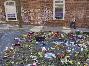 FILE- This Aug. 18, 2017 file photo shows a woman walking through the memorial at the site where Heather Heyer was killed in Charlottesville, Va. Heyer was struck and killed by a car while protesting a white nationalist rally on Aug. 12. The city of Charlottesville is preparing to dedicate a downtown street in her honor.