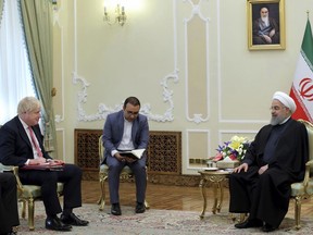 In this photo released by official website of the Office of the Iranian Presidency, Iranian President Hassan Rouhani, right, meets British Foreign Secretary Boris Johnson, left, at the presidency office in Tehran, Iran, Sunday, Dec. 10, 2017. Johnson arrived in Tehran on Saturday, where he was expected to discuss the fate of detained dual nationals, including a woman serving a five-year prison sentence for allegedly plotting to overthrow Iran's government. An unidentified interpreter sits at center. (Iranian Presidency Office via AP)