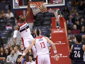 Washington Wizards guard John Wall (2) dunks during the first half of an NBA basketball game against the Memphis Grizzlies, Wednesday, Dec. 13, 2017, in Washington. Also seen is Wizards center Marcin Gortat (13) and Grizzlies forward Dillon Brooks (24).