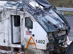 The engine from an Amtrak train crash onto Interstate 5 two days earlier is checked by workers before being transported away from the scene, Wednesday, Dec. 20, 2017, in DuPont, Wash. The Amtrak train that careened off the overpass south of Seattle, killing at least three people, was hurtling 50 mph over the speed limit when it jumped the track, federal investigators say.