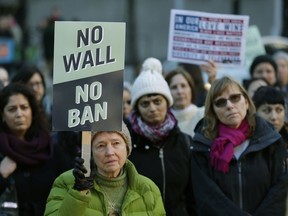 Annie Phillips, of Burien, Wash., holds a sign that reads "No Wall No Ban," during a protest, Wednesday, Dec. 6, 2017, outside a federal courthouse in Seattle. The U.S. Supreme Court decision allowing President Donald Trump's third travel ban to take effect has intensified the attention on a legal showdown Wednesday before three judges in Seattle who have been cool to the policy as they hear arguments in Hawaii's challenge to the ban, which restricts travel to the United States by residents of six mostly Muslim countries and has been reviled by critics as discriminatory.
