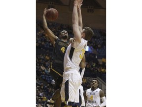 Coppin State guard Tre' Thomas (4) drives to the basket as West Virginia forward Logan Routt (31) defends during the first half of an NCAA college basketball game Wednesday, Dec. 20, 2017, in Morgantown, W.Va.