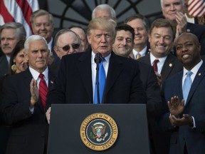 In this Dec. 20, 2017, photo, President Donald Trump, joined by Vice President Mike Pence, Speaker of the House Paul Ryan, R-Wis., and other members of congress, pauses as he speaks during an event on the South Lawn of the White House in Washington, to acknowledge the final passage of tax overhaul legislation by Congress. Two things can be true at once. President Donald Trump's tax overhaul is slanted to the rich, as Democrats say and Republicans like to ignore. It also comes with tax cuts for average people, which Democrats bypass in slamming Trump's "betrayal" of the middle class.