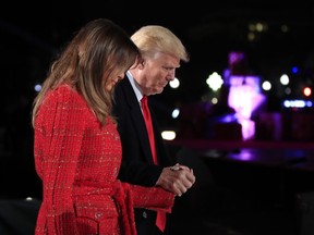 In this Nov. 30, 2017, photo, President Donald Trump holds first lady Melania Trump's hand as they walk back to the stage during the lighting ceremony for the 2017 National Christmas Tree on the Ellipse near the White House in Washington. There's a long tradition of presidents defending their first ladies, and it's now Trump's turn. Trump pushed back recently after Vanity Fair magazine, citing an anonymous source, reported that Melania Trump didn't want to become first lady "come hell or high water" and didn't think it would happen.