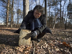 In this Dec. 14, 2017, photo Pastor Michelle Thomas stands over a headstone as she gives a tour of slave burial grounds that rest on a three-acre tract at a busy northern Virginia intersection that once served as a slave cemetery in Loudoun County in Ashburn, Va.  After almost two years of difficult negotiations, a northern Virginia developer agreed to give the tract to the Loudoun Freedom Center, founded by Thomas, to preserve the site and learn more about it.
