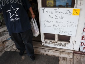 FILE - In a Wednesday, July 16, 2014 file photo, a customer exits the Aladdin General Store where a handwritten sign is posted: "This town is for sale" in northeast Wyoming. Aladdin, a small town in northeast Wyoming that features an historic mercantile building will see a change in ownership soon. The couple who have owned the town, with a population of 15 residents, for the last 31 years has accepted an offer from a group of investors led by an Arizona businessman to buy the town. (Daniel Brenner/Gillette News Record via AP, File
