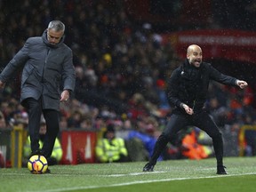 Manchester City coach Pep Guardiola, right, gestures while Manchester United coach Jose Mourinho stops a stray ball during the English Premier League soccer match between Manchester United and Manchester City at Old Trafford Stadium in Manchester, England, Sunday, Dec. 10, 2017.