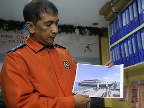 Coast guard spokesman Armand Balilo shows a file photo of passenger vessel Mercraft 3 as he talks to reporters in Manila, Philippines on Thursday, Dec. 21, 2017. Philippine officials say coast guard officials and fishermen are trying to rescue more than 200 people on an inter-island ferry which is sinking off a northeastern province.