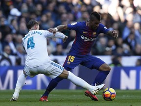 Barcelona's Paulinho fights for the ball with Real Madrid's Sergio Ramos, left, during the Spanish La Liga soccer match between Real Madrid and Barcelona at the Santiago Bernabeu stadium in Madrid, Spain, Saturday, Dec. 23, 2017.