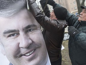Supporters of former Georgian President Mikheil Saakashvili set a portrait of him on a tree as they gather outside the police station where he was taken in Kiev, Ukraine, Saturday, Dec. 9, 2017. From his jail cell in Ukraine's capital, opposition leader Mikheil Saakashvili is calling on supporters to rally for the impeachment of the president and has declared a hunger strike.