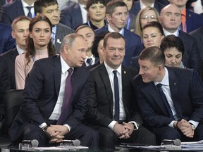 Russian President Vladimir Putin, foreground left, speaks to Russian Prime Minister Dmitry Medvedev, center, and acting Secretary of the General Council of United Russia Andrey Turchak , right, at the United Russia party congress in Moscow, Russia, Saturday, Dec. 23, 2017. Putin will speak about his plans at a congress of the main Kremlin party, the United Russia, to spell out his program as he runs for re-election.