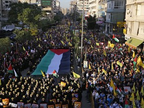 Tens of thousands of Lebanese and Palestinians march in a street as they hold a giant Palestinian flag in response to a call by Hezbbollah leader Sheikh Hassan Nasrallah to protest U.S. President Donald Trump's decision to recognize Jerusalem as the capital of Israel, in a southern suburb of Beirut, Lebanon, Monday, Dec. 11, 2017.