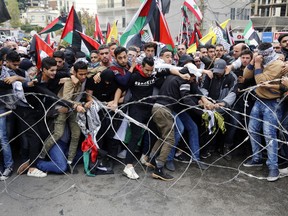 Protesters try to remove barbed wires that block a road leading to the U.S. embassy during a demonstration in Aukar, east of Beirut, Lebanon, Sunday, Dec. 10, 2017. Scores of demonstrators, including Palestinians, pelted security outside the embassy with stones and burned an effigy of U.S. President Donald Trump in a protest to reject Washington's recognition of Jerusalem as capital of Israel.