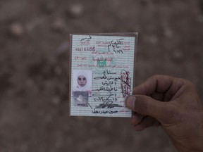 Fifteen-year-old Sana Younes died in a mortar attack in Mosul during the final battle to drive out Islamic State extremists, and her body was exhumed months later for forensic investigation. In this Oct. 9, 2017, photo, her brother Salem holds her identification card before her remains are reburied.