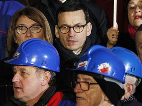 Poland's new Prime Minister Mateusz Morawiecki, background centre, attends ceremonies in Warsaw, Poland on Wednesday, Dec. 13, 2017, marking 36 years since the communist authorities of the time imposed martial law in Poland intending to crush the massive independence Solidarity movement, which eventually prevailed leading to the ouster of the communist regime.