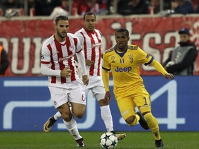 Juventus' Douglas Costa, right, and Olympiakos' Panagiotis Tachtsidis run for the ball during the Champions League group D soccer match between Olympiakos and Juventus at Georgios Karaiskakis stadium at Piraeus port, near Athens, Tuesday, Dec. 5, 2017.