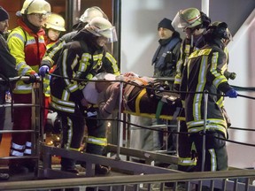 In this Dec, 26, 2017 photo, rescuers carry an injured passenger off a damaged tourist ship in Duisburg, Germany.  A tourist ship has struck a highway bridge on the Rhine river in western Germany. Police say 27 people are injured. The Swiss Crystal, which news agency dpa reports was en route to the Netherlands, hit a pillar of the bridge near Duisburg on Tuesday evening.