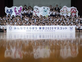 Children and officials of Tokyo 2020 pose for photographers with cutouts of shortlisted three mascot design sets which each contain one mascot for the Tokyo Olympic Games and one for the Paralympic Games, at an elementary school in Tokyo Thursday, Dec. 7, 2017.