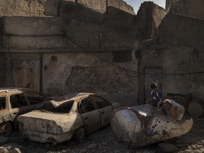 In this Nov. 16, 2017 photo, Mohammed Tahar, right, and his grandson Mustafa Hansen, remove debris from the sidewalk leading to their house in the Old City of Mosul, Iraq. While 2.7 million Iraqis have returned to lands seized back from Islamic State, more than 3 million others cannot. Of those around 600,000 are from Mosul.