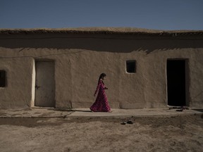 In this Nov. 12, 2017 photo, a girl walks outside her home in the Bijwaniya village, south of Mosul, Iraq. Five young men were taken by unidentified gunmen after the village was liberated from Islamic State militants and despite months of searching; their families haven't been able to locate them.