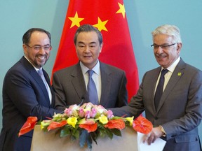 From left, Afghanistan Foreign Minister Salahuddin Rabbani, Chinese Foreign Minister Wang Yi and Pakistani Foreign Minister Khawaja Asif hold hands to pose for a photo after a press conference for the 1st China-Afghanistan-Pakistan Foreign Ministers' Dialogue held in Beijing, China, Tuesday, Dec. 26, 2017.