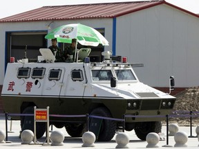 In this Nov. 3, 2017 photo, paramilitary policemen in an armored vehicle are on duty at the airport in Hotan in western China's Xinjiang region. Authorities are using detentions in political indoctrination centers and data-driven surveillance to impose a digital police state in the region of Xinjiang and its Uighurs, a 10-million strong, Turkic-speaking Muslim minority Beijing fears could be influenced by extremism.