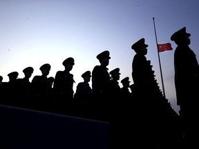 Chinese paramilitary policemen stand at attention near a Chinese flag flown at half mast to mark the 80th anniversary of the Nanjing massacre held at the Memorial Hall of the Victims in Nanjing Massacre by Japanese troops in Nanjing in eastern China's Jiangsu province Wednesday Dec. 13, 2017. (Chinatopix Via AP)